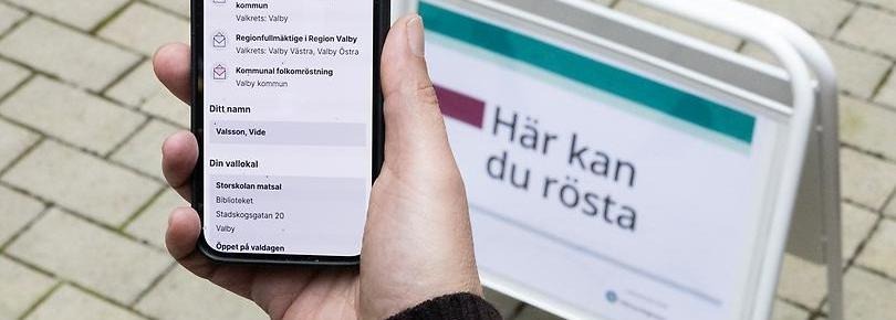 Telefon i hand+skylt: Här kan du rösta.