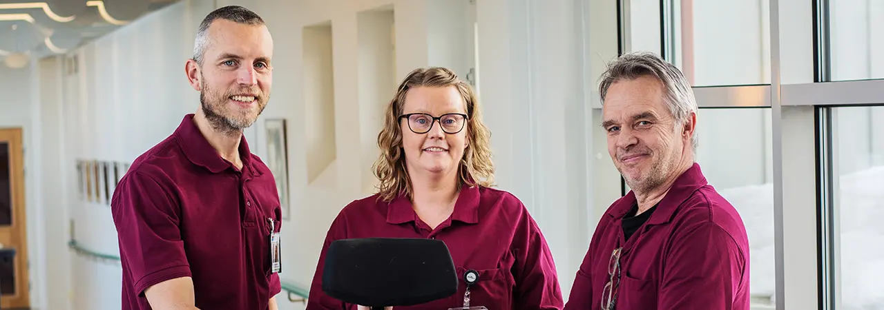 Tre arbetsterapeuter i röda jobbkläder.