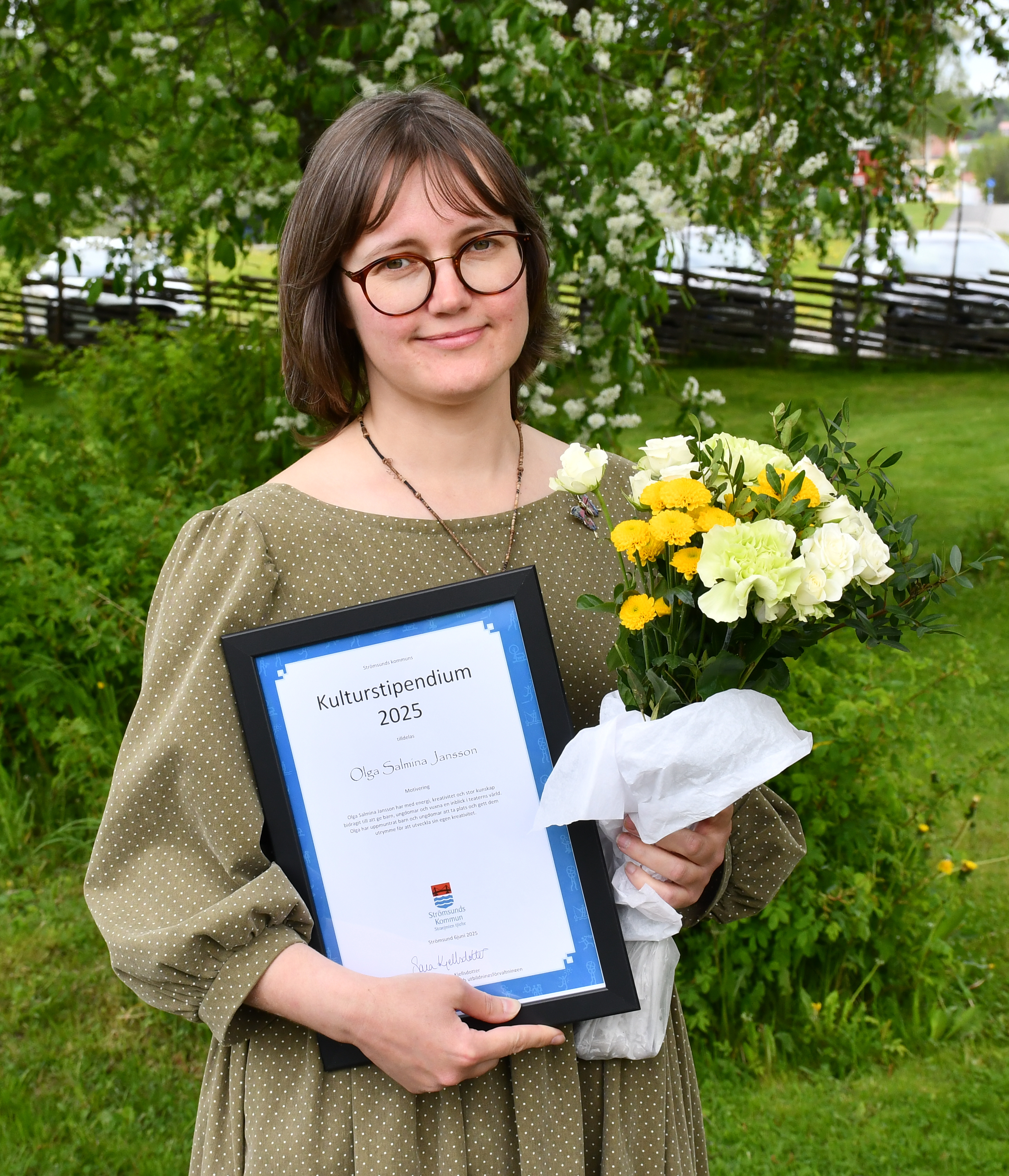 Kvinna som håller i blommor och ett diplom.