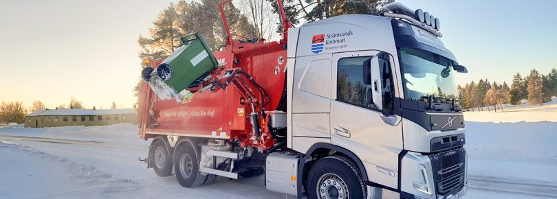 En röd och vit lastbil som kör på en snötäckt väg.