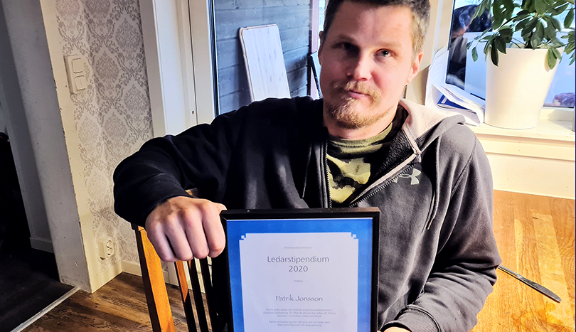 Glad man med diplom i famnen.
