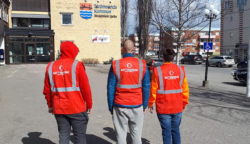 Tre personer i orange skyddsvästar