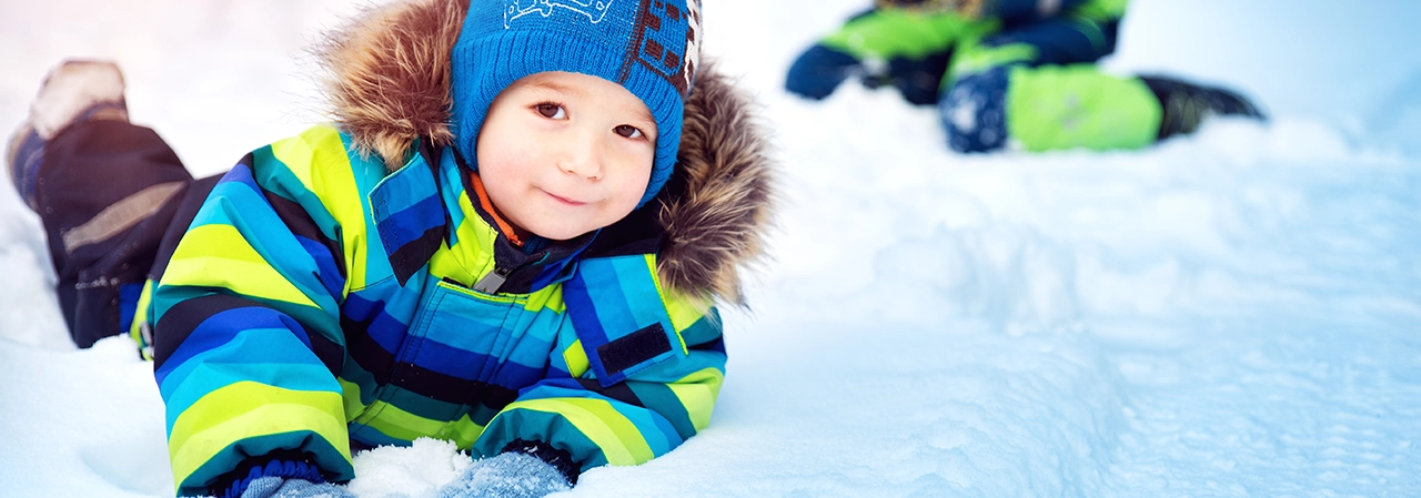 Liten pojke leker i snö.