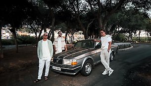 Tre ljust klädda killar vid en Volvo.