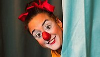 Clown tittar fram bakom en gardin.